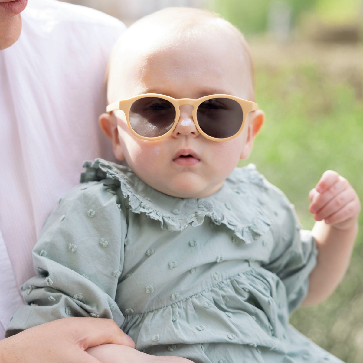 Baby mit Sonnenbrille im Garten